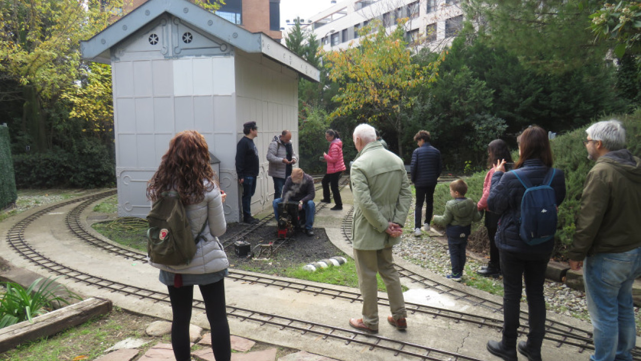 Participantes en el parque 'Ferrocarril de las Delicias' asistiendo al encendido de una pequeña locomotora de vapor.