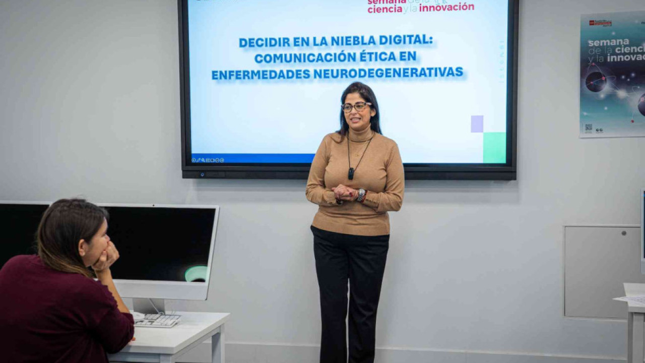 La Doctora Bárbara Castillo Abdul explica una presentación sobre comunicación ética en enfermedades neurodegenerativas ante un pequeño grupo en un aula informática
