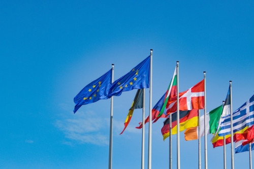 Dos banderas de Europa ondean en el cielo, con otras banderas de países europeos tras ellas.